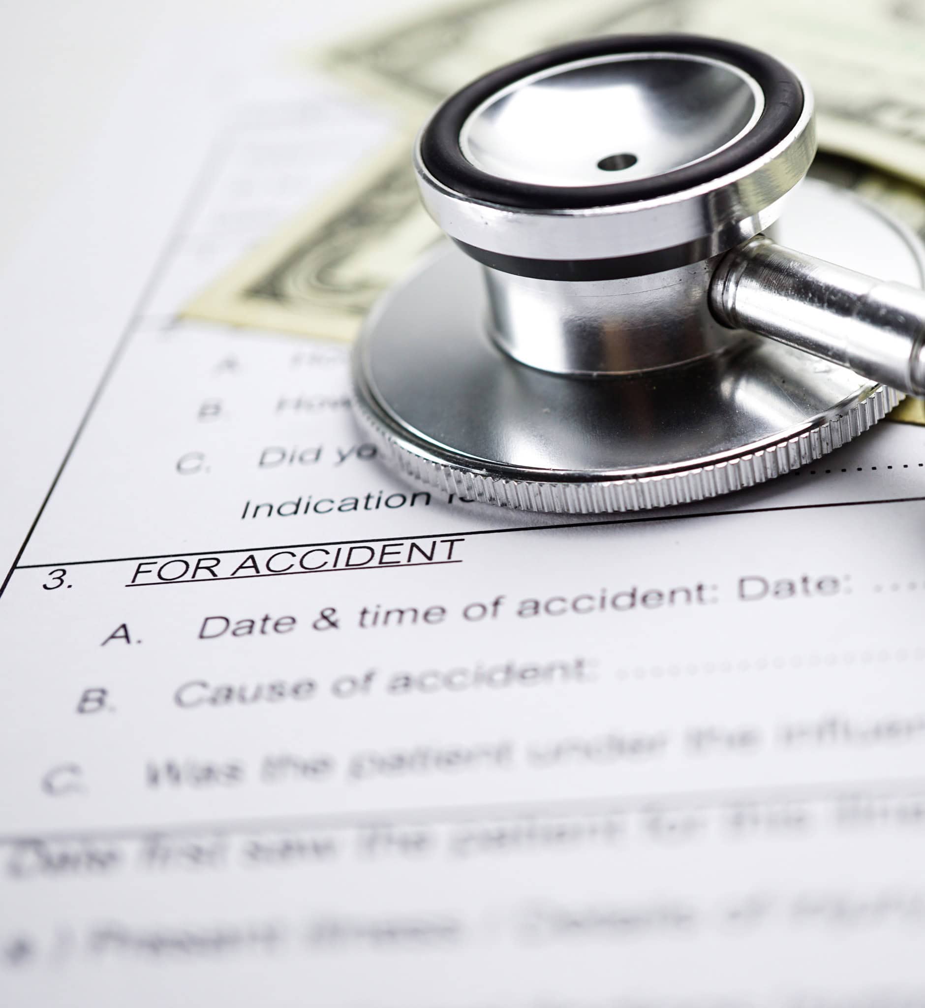Stethoscope resting on health insurance accident claim form with US dollars